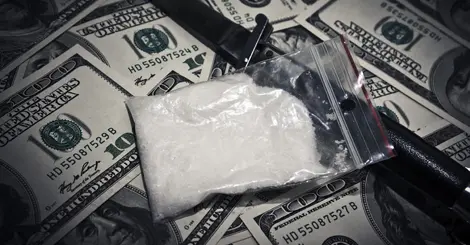 a bag of white powder sitting on top of a pile of money.