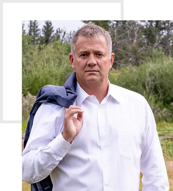 Fleener Peterson Law attorney Tom Fleener standing in a field with his jacket over his shoulder.